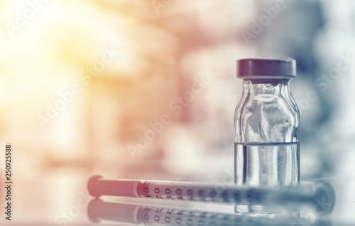 Closeup of medicine vial or flu, measles vaccine bottle with syringe and needle for immunization on vintage medical background, medicine and drug concept photo