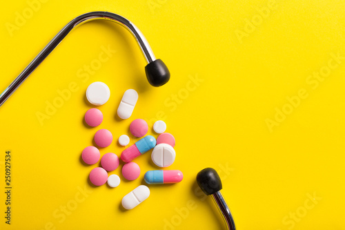 Assorted pharmaceutical medicine pills, tablets and capsules. Yellow background. photo