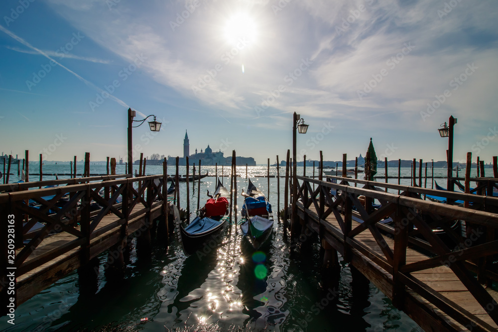 Venice italian city view with gondolas parked at seashore, channels and bridges, sea and clouds sky landscape at sunny day in Italy, tourism and travelling, travel tourist destination famous landmark Venice italian city view with gondolas parked at seashore, channels and bridges, sea and clouds sky landscape at sunny day in Italy, tourism and travelling, travel tourist destination famous landmark