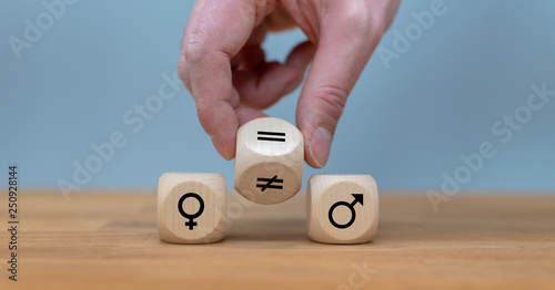 Symbol for gender equality. Hand turns a dice and changes a unequal sign to a equal sign between symbols of men and women. photo