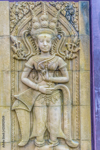 An Apsara dancing carved on the sandstone wall background. Apsara is a female spirit of the clouds and waters in Hindu culture. Her figure prominently in the sculpture  dance  literature and painting.
