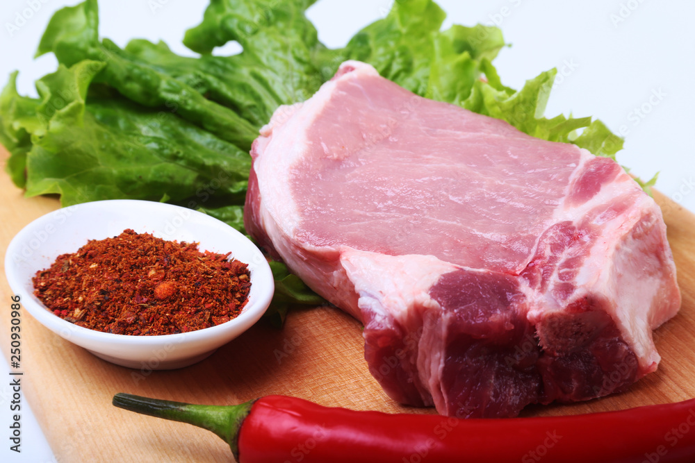 Fototapeta premium Raw pork chops with herbs and spices on cutting board. Ready for cooking.