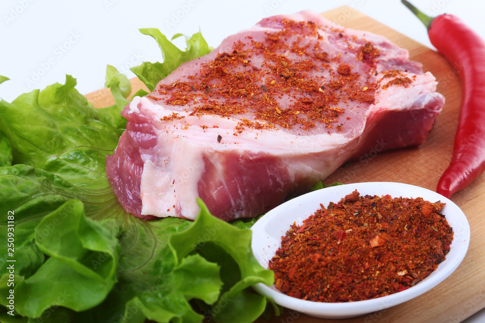 Fototapeta premium Raw pork steak with herbs, chili pepper and spices on cutting board. Ready for bbq.