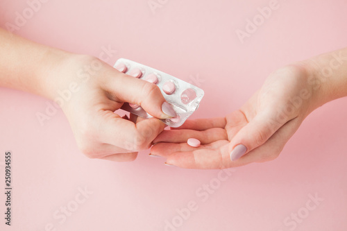 Pink pills tablets in the woman hand on pink background. Top view. Flat lay. Copy space. Medicine concept