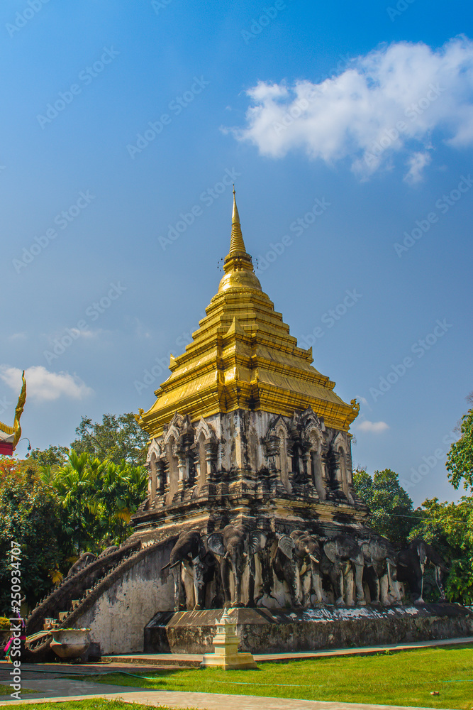 Fototapeta premium Old elephant chedi with golden top pagoda at Wat Chiang Man or Wat Chiang Mun, the oldest temple in Chiang Mai, Thailand, built in 1296 by King Mengrai in Lanna-style with elephant-shaped buttresses.
