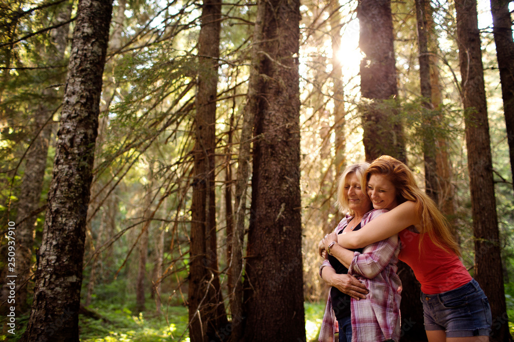 Young female embracing mother sunlight in forest Young female embracing mother sunlight in forest