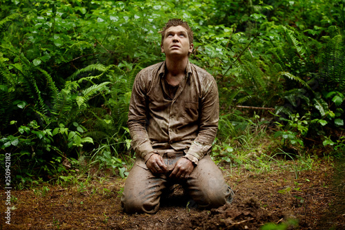Man kneeling on rainforest path 
