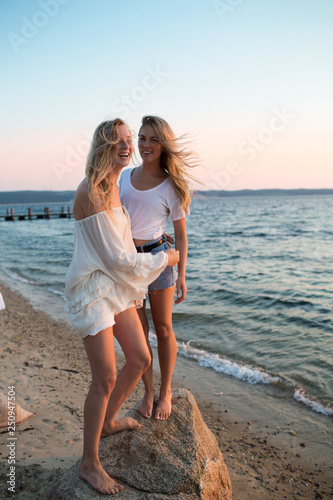 Two young women playing on beach at sunset  photo