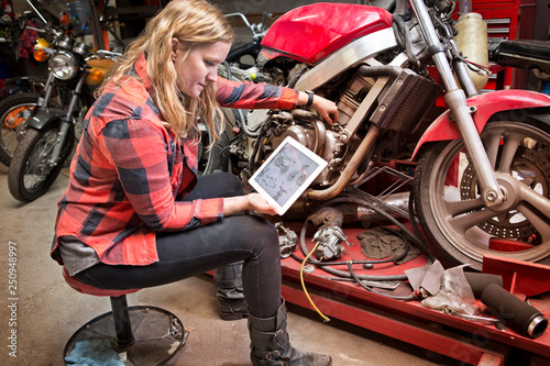 Female mechanic using digital tablet for repairing motorcycle  photo