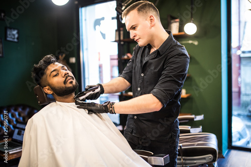 Young client during beard and moustache grooming in barber shop