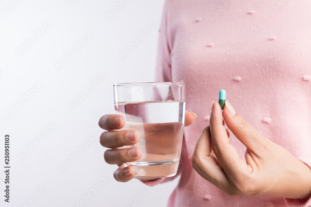 medicine, health care and people concept - close up of woman taking in pill and another hand holding a glass of clean mineral water. medicine, health care and people concept - close up of woman taking in pill and another hand holding a glass of clean mineral water.