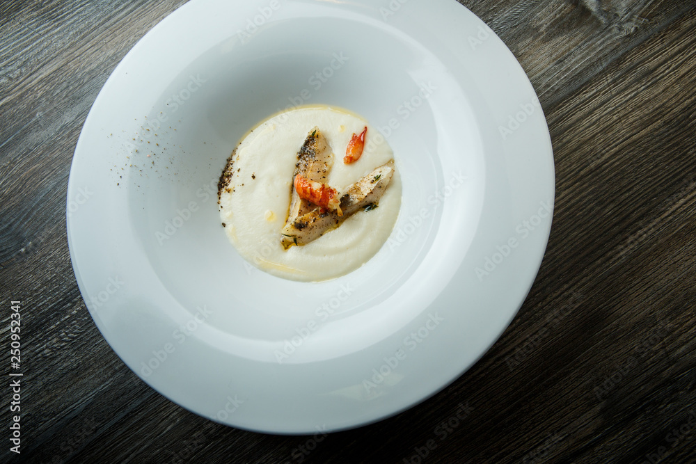 top view closeup white fish cream soup decorated with fried pieces of fish and prawn top view closeup white fish cream soup decorated with fried pieces of fish and prawn