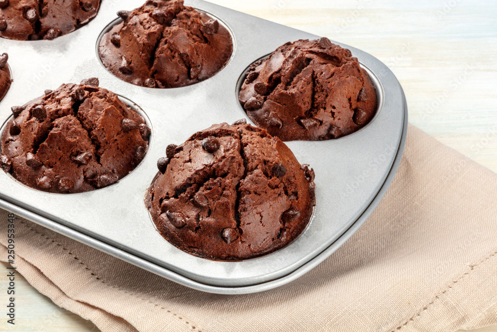 A closeup photo of chocolate chip muffins in a pan on a light background A closeup photo of chocolate chip muffins in a pan on a light background