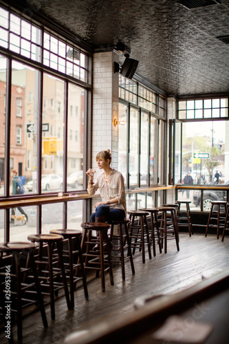 Young woman sitting by window in bar 