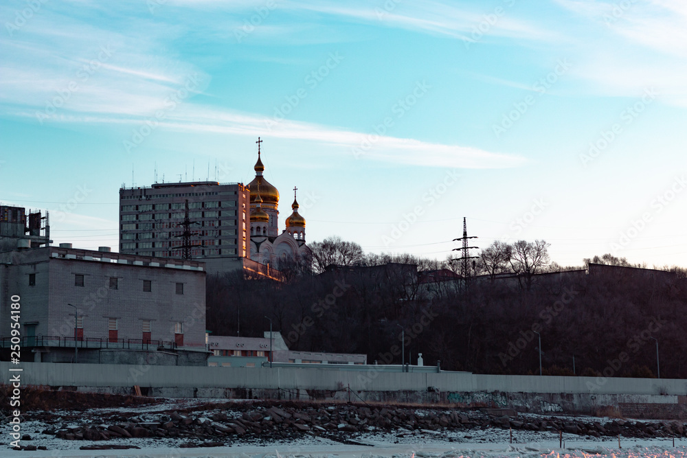 Fototapeta premium View of the city of Khabarovsk from the Amur river at dawn. Frozen river. The industrial look.