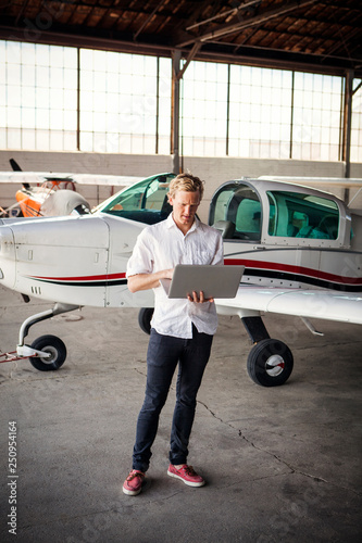 Man standing in hangar using laptop  photo