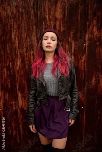 beautiful woman with red hair in black jacket posing about a wood wall on background