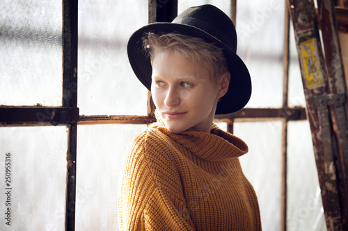 Portrait of young woman wearing hat in front of window 