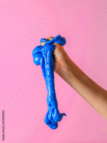 An blue slime flows down from the baby's hand on a pink background.