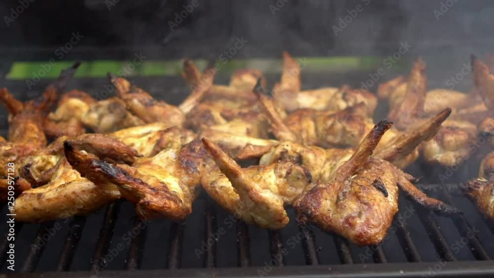 Hand of man open the door of BBQ grill. Cooking delicious chicken wings on grilled meat. Baking hot and spicy grill chicken wings in the oven. Delicious food cooked with grilling barbecue-Dan Hand of man open the door of BBQ grill. Cooking delicious chicken wings on grilled meat. Baking hot and spicy grill chicken wings in the oven. Delicious food cooked with grilling barbecue-Dan