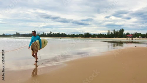 A surfer walking along the beach with a board in his hands