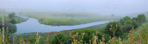 Foggy summer landscape with river bend and meadows