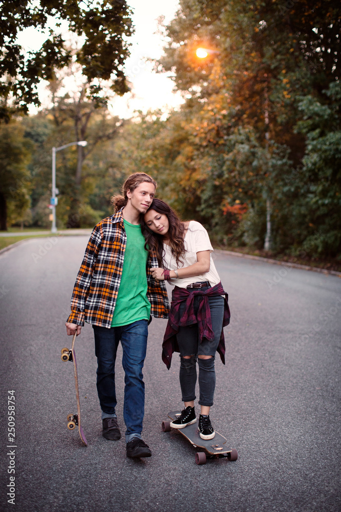 Young couple with skateboards in park Young couple with skateboards in park