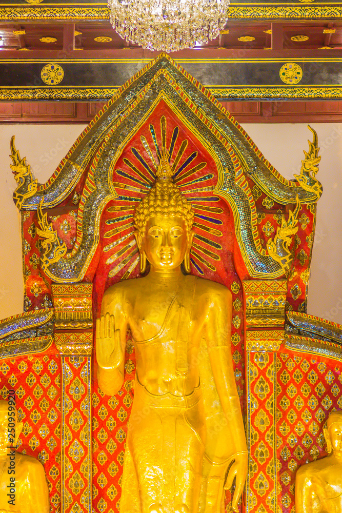 Fototapeta premium Beautiful large standing golden Buddha image with ceiling interior decoration, named Phra Chao Attarot at Wat Chedi Luang (temple of the big royal stupa), located in Chiang Mai, Thailand.