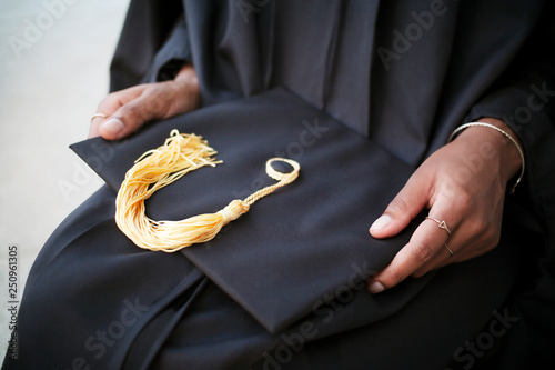 Mid-section of woman holding mortarboard 