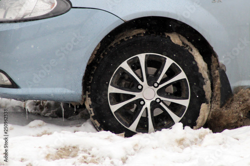 Car wheel with studded tire standing on winter road with deep snow