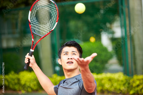 young asian man playing tennis outdoors © imtmphoto