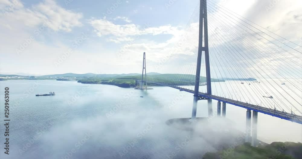 Ascending aerial view of Russian bridge, the longest cable-stayed bridge in the world. It connects the Russky Island and Vladivostok across the Eastern Bosphorus strait. Misty morning