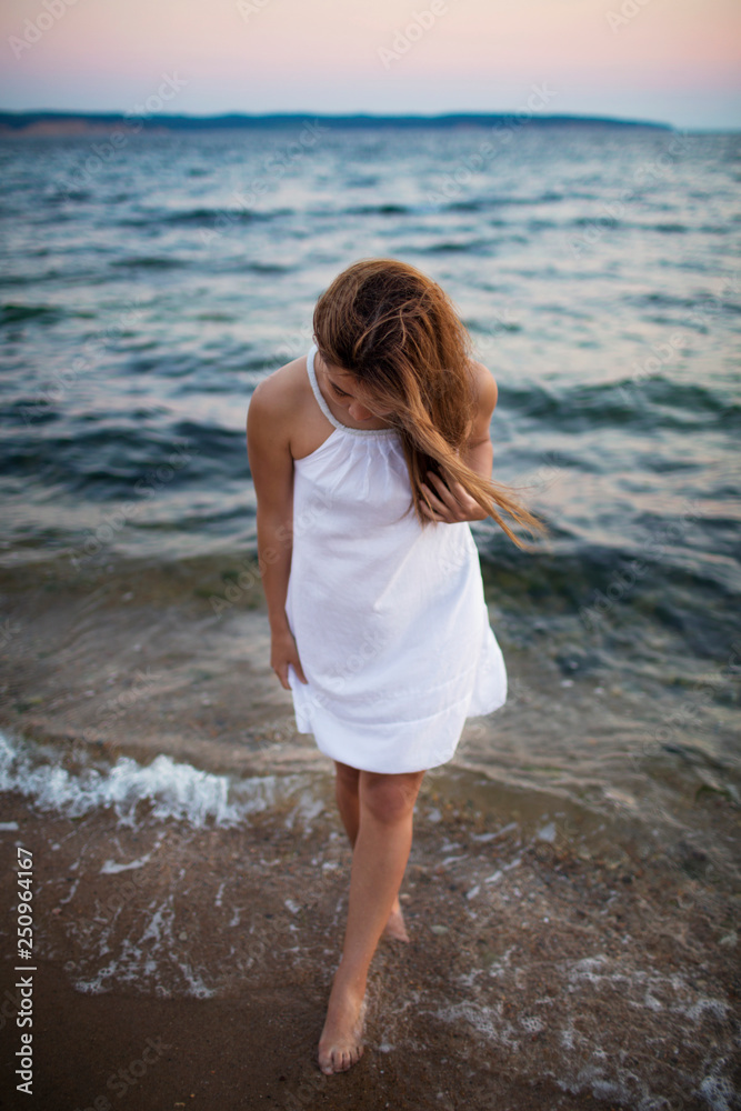 Young woman wading in sea at sunset Young woman wading in sea at sunset