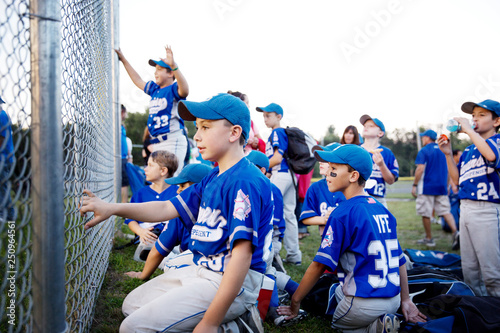 Little league team (8-9, 10-11) cheering from behind fence 