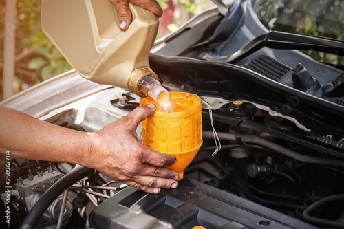 The car mechanic is adding oil to the engine, Automotive industry and garage concepts.