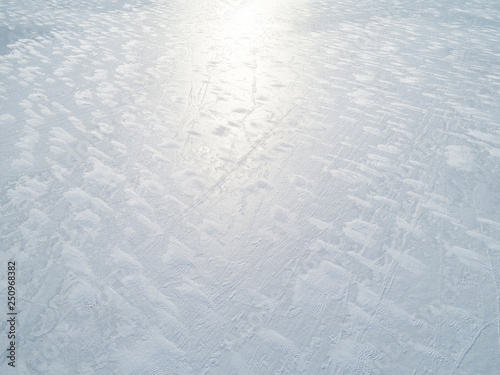 Aerial view of a frozen lake surface. Aerial Snow pattern on the frozen lake. Frozen lake ice captured with a drone. Aerial photography. Winter snow texture.