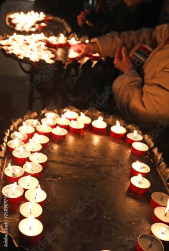 women light candles by reciting prayers inside the church