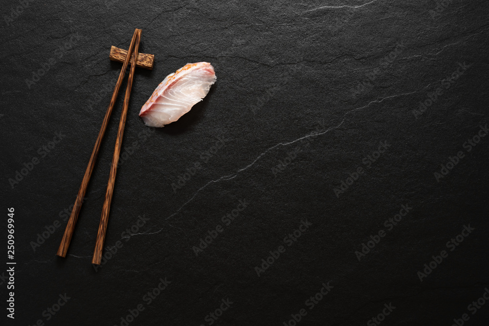 space wood chopstick with fish slice on black marble background space wood chopstick with fish slice on black marble background