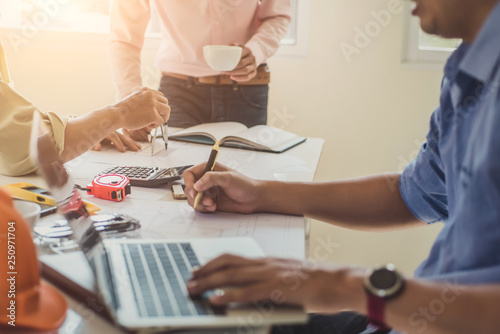 Close up hand of civil engineer or architect business working on blueprint architectural project at construction site at desk in office.