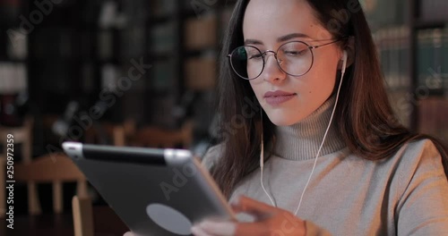 Female university student typing on tablet in library