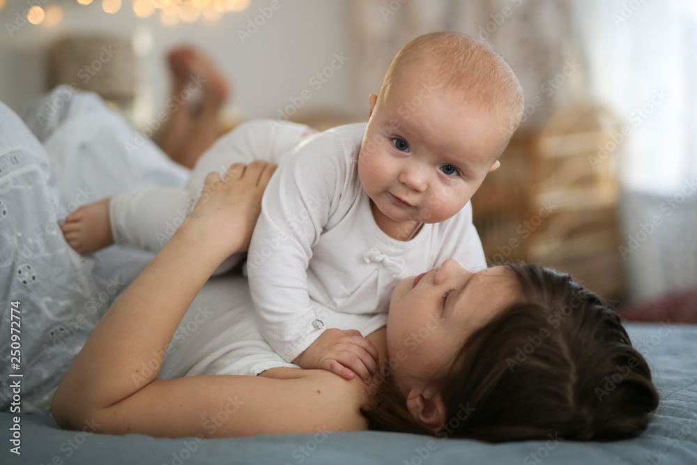 girl holds baby in her arms on bed. Lifestyle girl holds baby in her arms on bed. Lifestyle