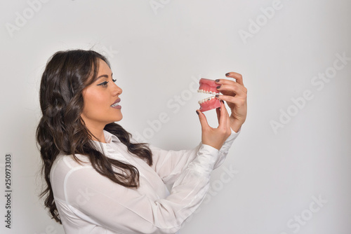 Young woman isolated on white, holding a dental model.