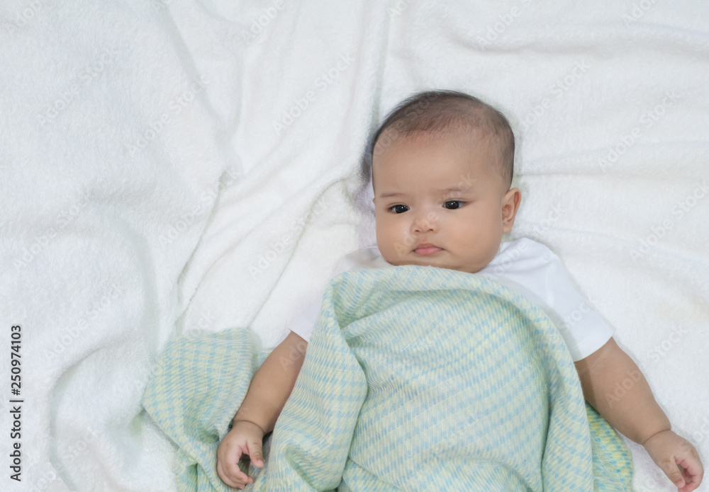 Asian newborn baby wear white shirt under light green blanket on white towel background