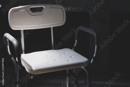 Plastic bathing chair for elder or disabled people showering put in dark letting light come from left side