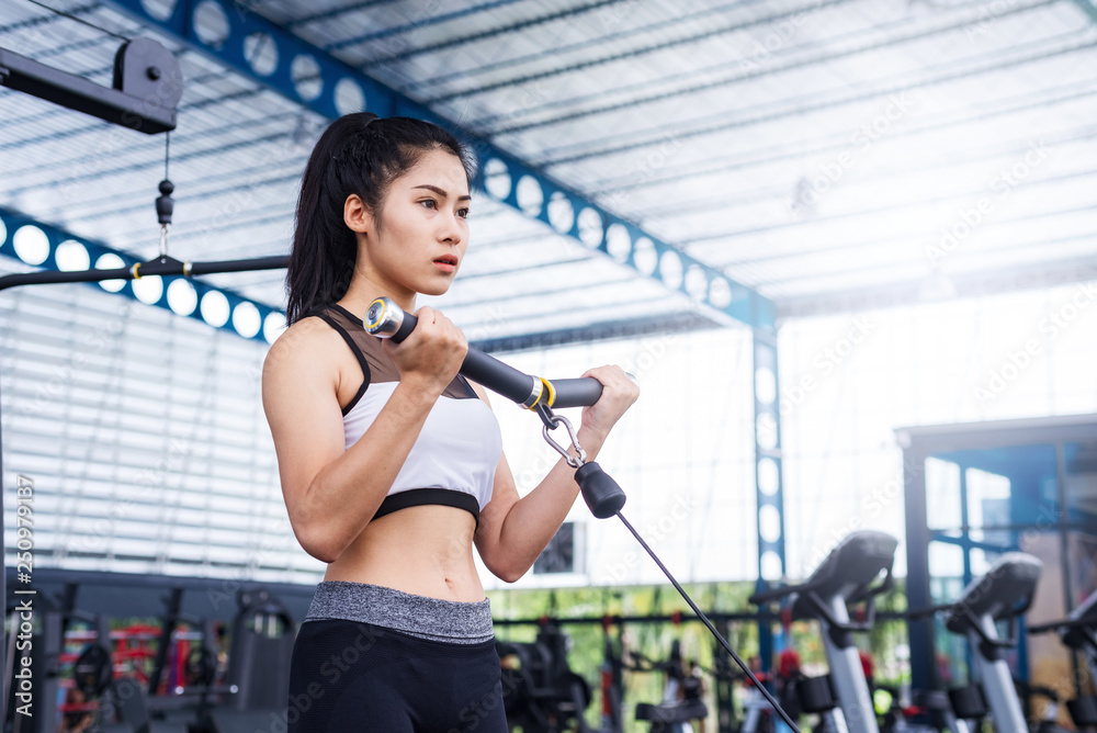 Fototapeta premium fitness woman exercise workout with exercise-machine Cable in fitness gym. healthy lifestyle Concept