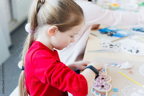 The girl is engaged in creating a mosaic in a creative workshop.