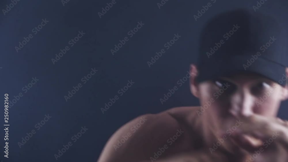 Fierce man with shirt off bare knuckle boxing and punching at the camera on black background