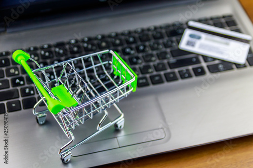 Online shopping concept. Small shopping cart and credit card on laptop keyboard