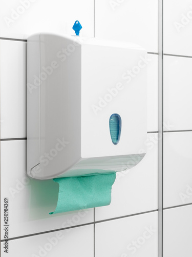 Holder or dispenser for paper towels on the wall tiles in a public toilet photo