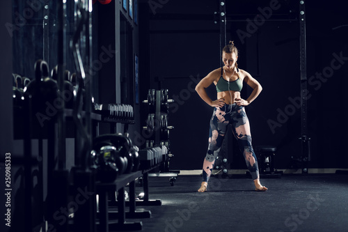 Caucasian strong woman in sportswear and with pigtail standing barefoot in gym with hands on hips. © dusanpetkovic1